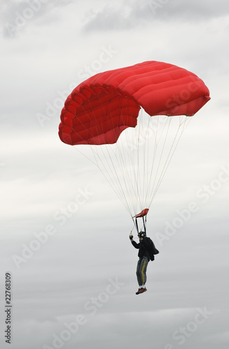 Parachuter with red parachute landing in bad weather