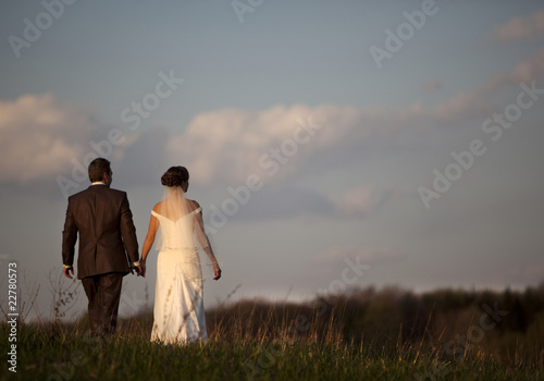 young bride and groom against blue sky with clouds
