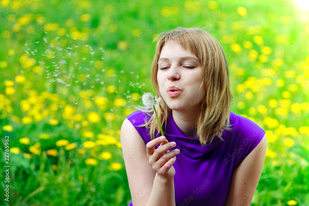 Beautiful woman blowing dandelion on the meadow Beautiful woman blowing dandelion on the meadow