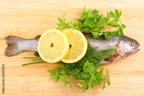 Raw fish with lemon and parsley on wooden background
