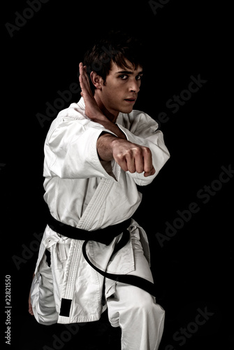 High Contrast karate young male fighter on black background.