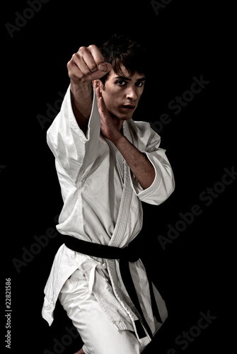 High Contrast karate young male fighter on black background.