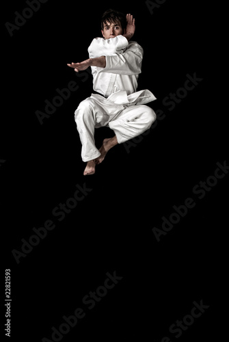 High Contrast karate young male fighter jump on black