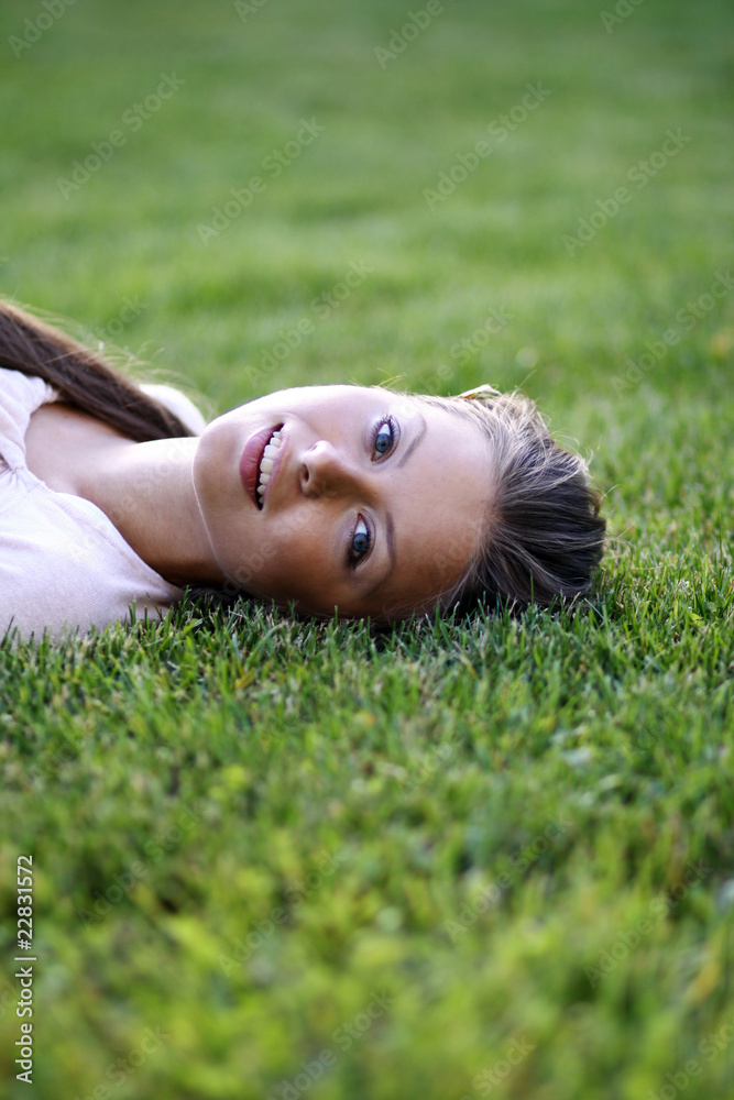 Cute young female lying on grass field at the park . Cute young female lying on grass field at the park .
