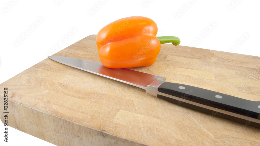 pepper and carving knife on chopping block on white pepper and carving knife on chopping block on white