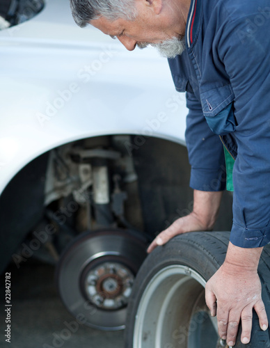 mechanic changing a wheel of a modern car (color toned image)