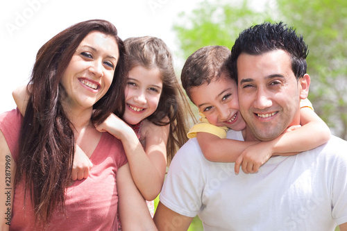 Couple giving two young children piggyback rides smiling