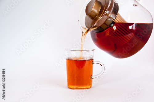 Pouring hot black tea into glass