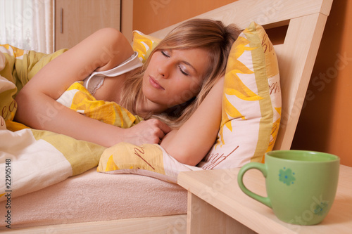 A cup of cofee or tea at bedroom, in background sliping woman