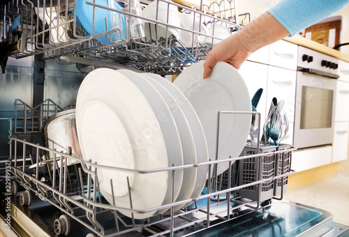 female hands loading dishes to the dishwasher
