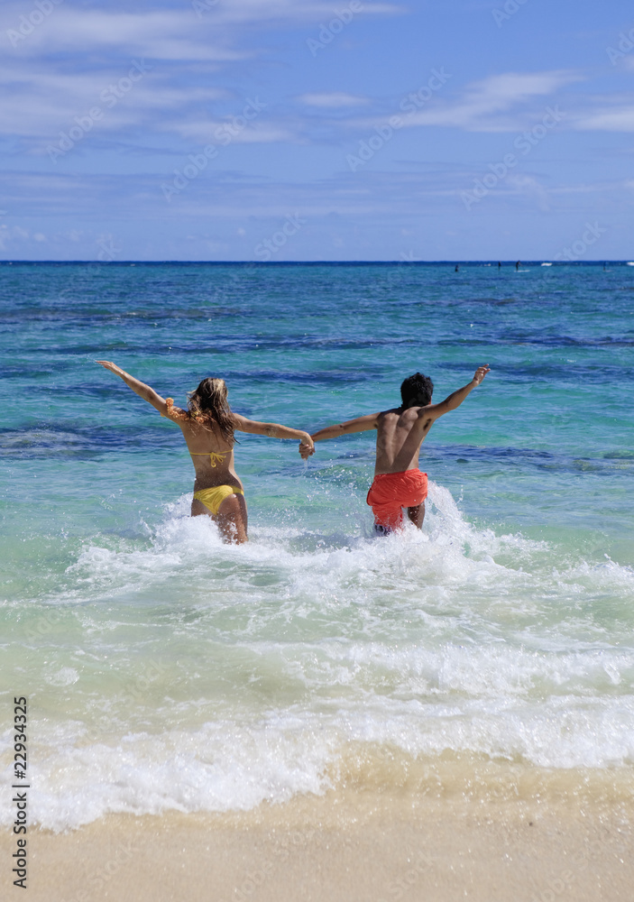 young couple runs into the ocean young couple runs into the ocean