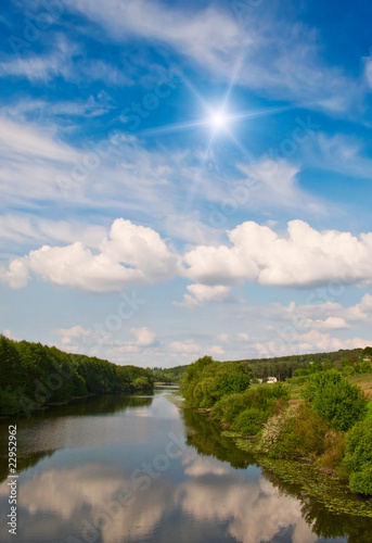 Fototapeta Naklejka Na Ścianę i Meble -  Small river and sun in the blue sky.