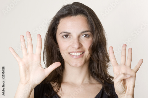 Hübsche Frau zeigt mit neun Fingern die Zahl 9 an