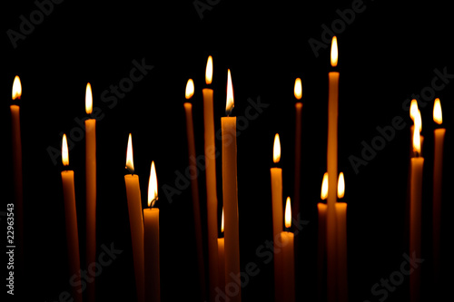 Lot of long lighted candles on a black background