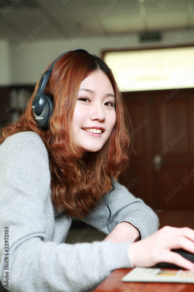 Asian girl sitting in front of the computer listening music Asian girl sitting in front of the computer listening music