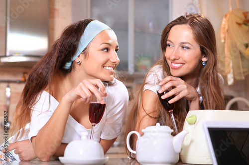 Happy women with wine in kitchen