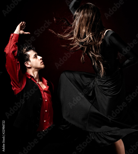 Young couple passion flamenco dancing on red light background.