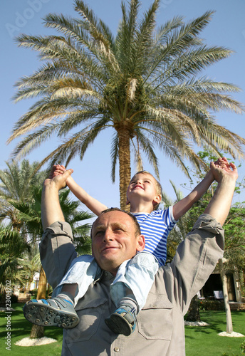 senior with child on shoulders in front of palm tree collage