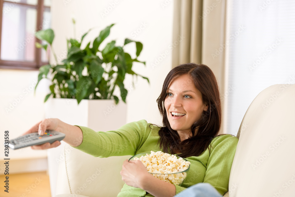 Woman watching television with popcorn in living room Woman watching television with popcorn in living room