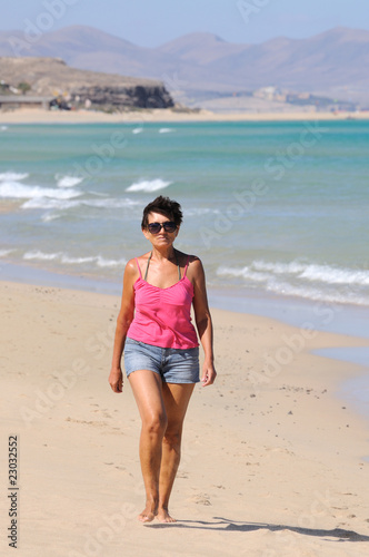 Senior woman walking on the beach photo