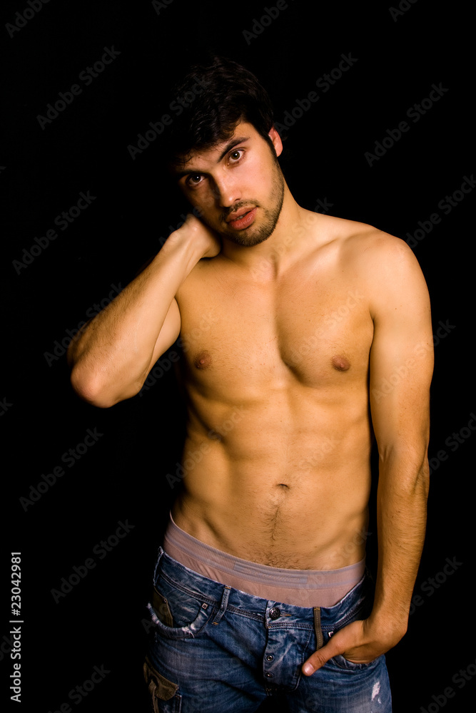 Fototapeta premium Young man with atletic body on black background