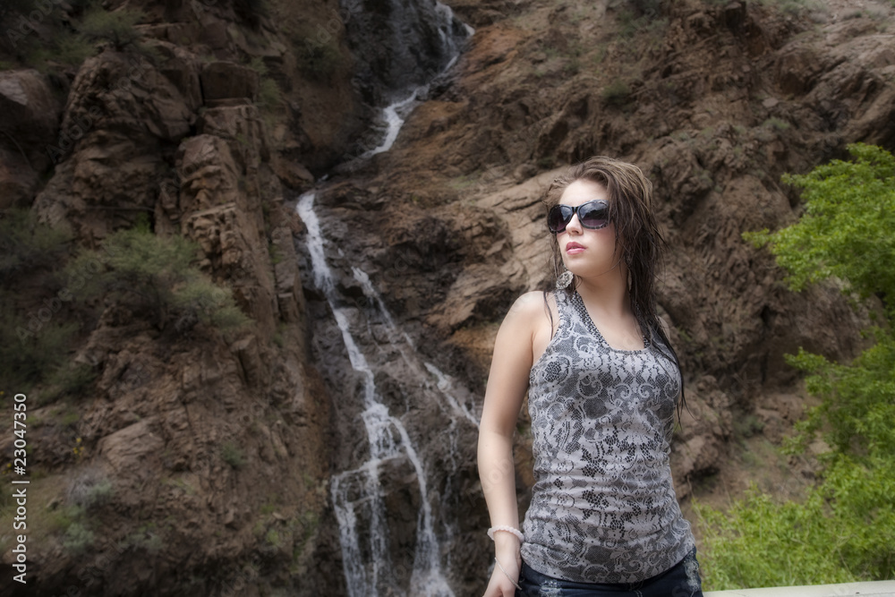 Woman with sunglasses by waterfall