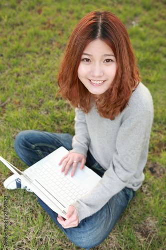asian girl with laptop on grassland © zhu difeng