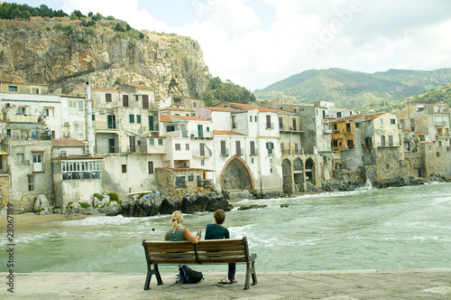 Couple sitting on a bench near the ocean in Cefalu, Sicily