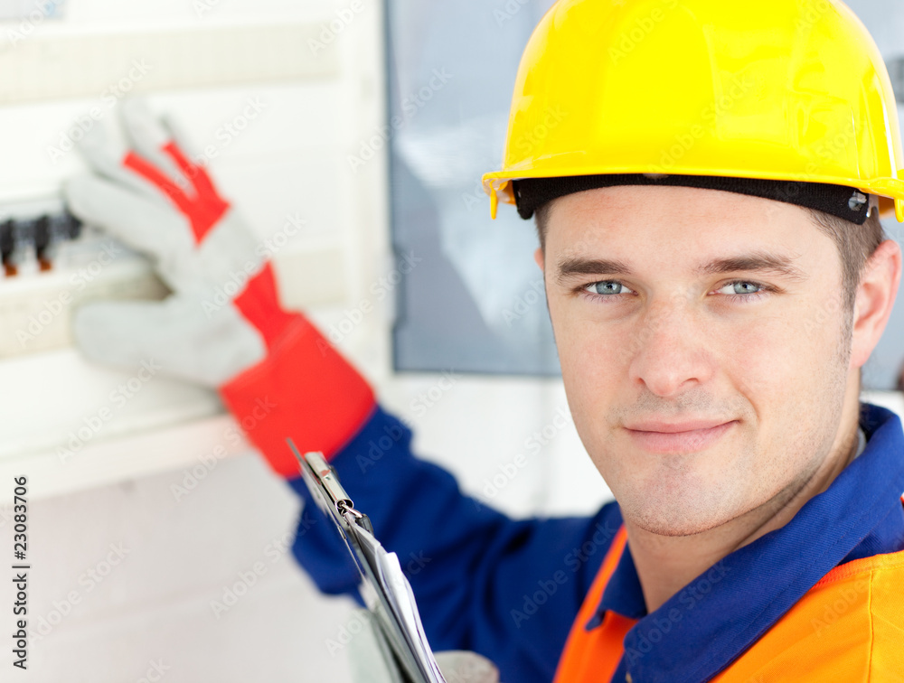 Smiling electrician repairing a power plan Smiling electrician repairing a power plan