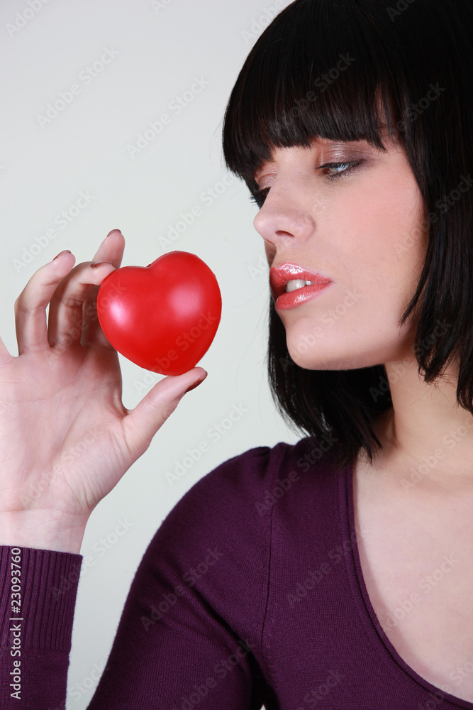 Jeune femme avec cœur en plastique rouge Jeune femme avec cœur en plastique rouge