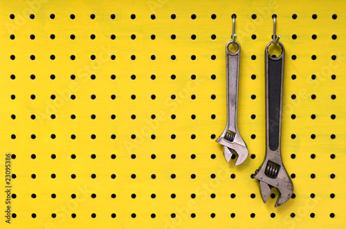 Принти на полотні Two wrenches hang from hooks on yellow pegboard