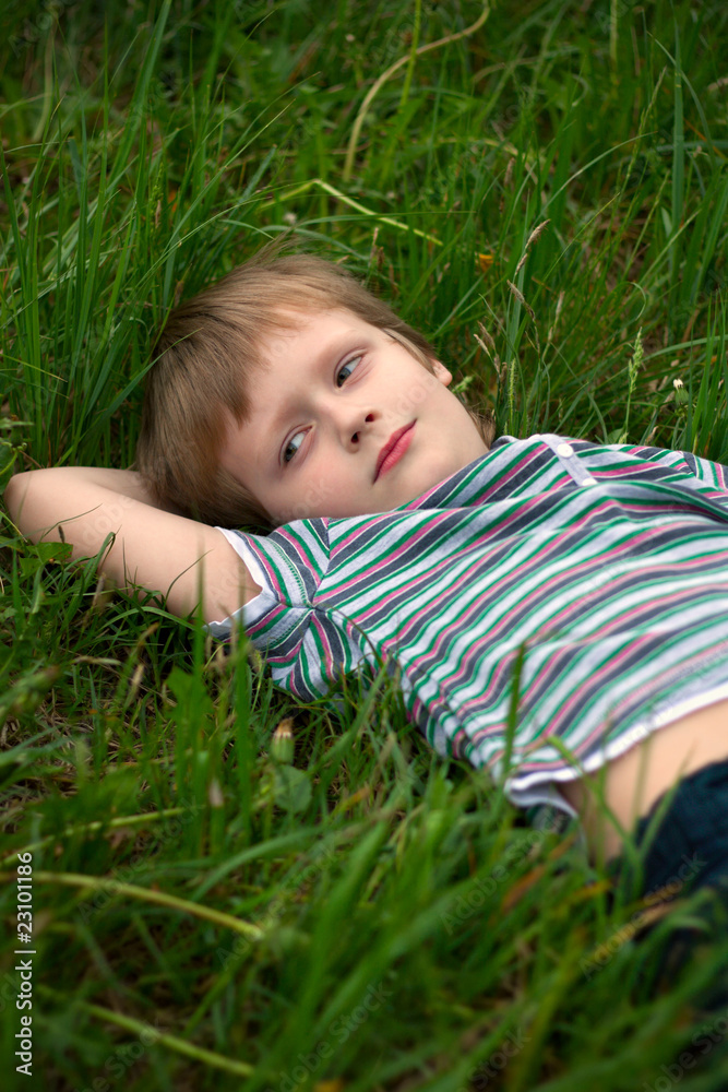 The little boy has laid down on a grass to dream The little boy has laid down on a grass to dream