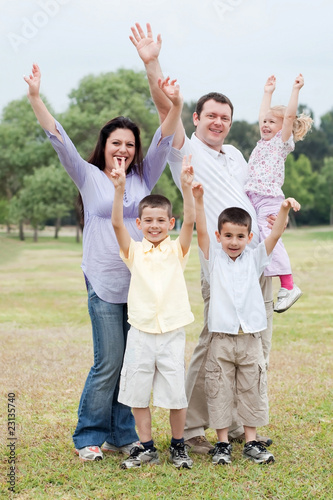 Happy family on outdoors enjoying by raising hands
