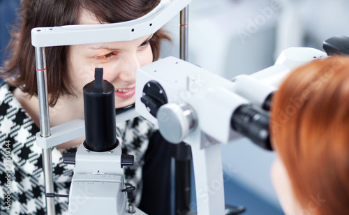 optometry concept - pretty young woman having her eyes examined