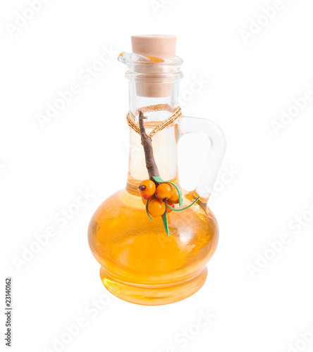 Jug with vegetable oil and sea-buckthorn berries branch