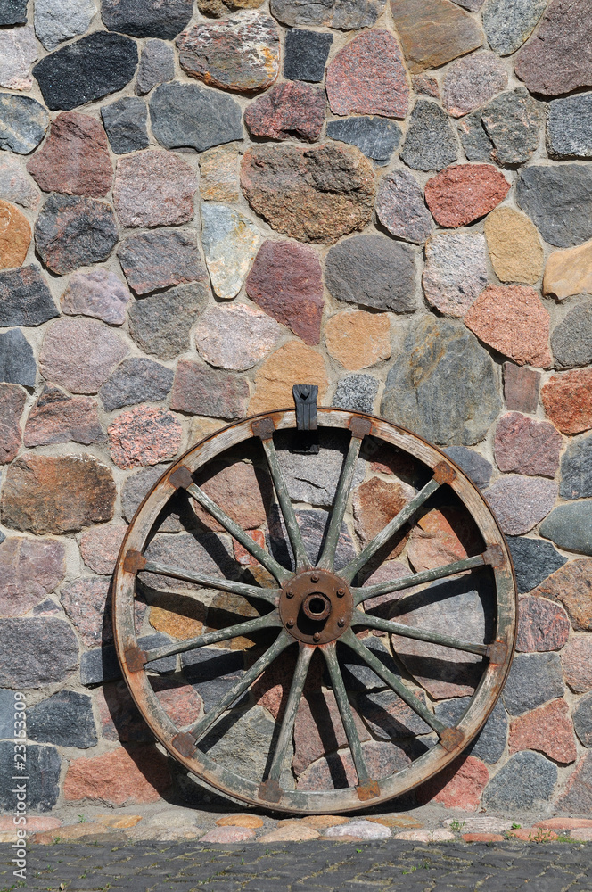 Old wagon wood wheel against an house wall