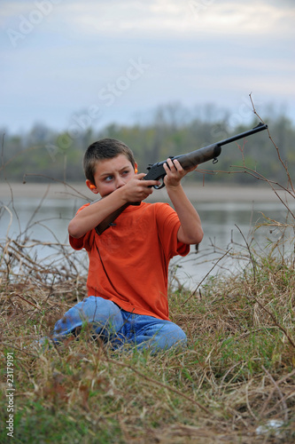 Boy aiming rifle upward