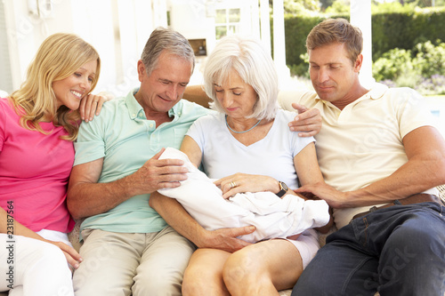 Extended Family Relaxing Together On Sofa With Newborn Baby
