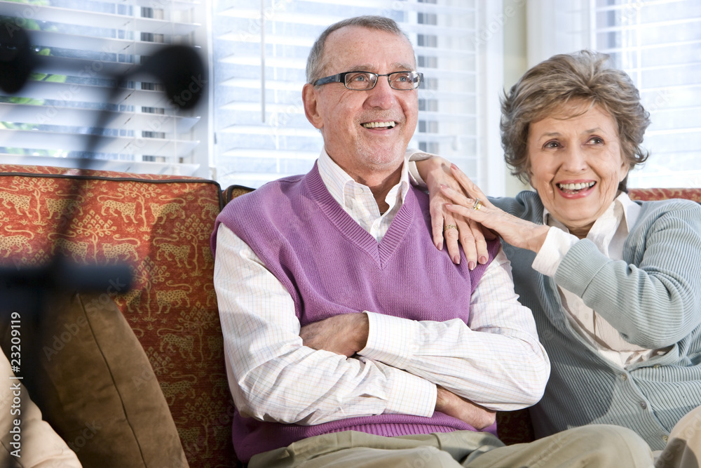 Obraz premium Happy senior couple sitting together on couch