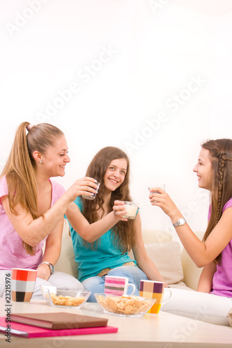 Three young girls sitting in the living room and having a drink