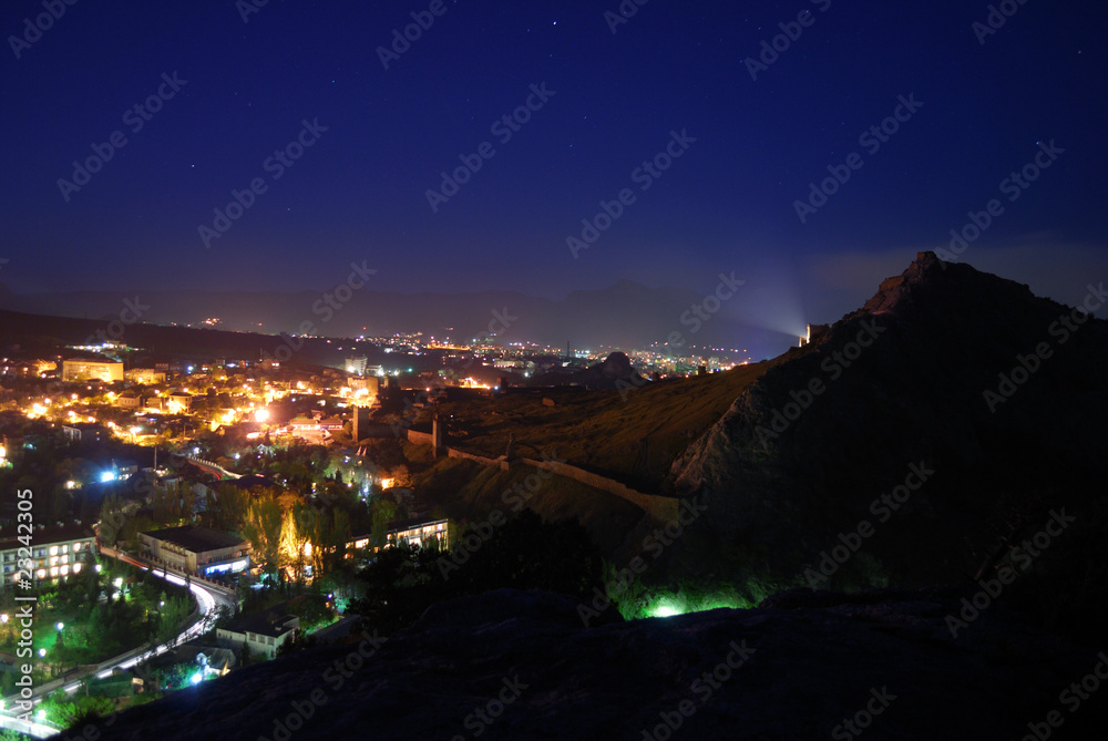 Night city and ancient fortress on the hill