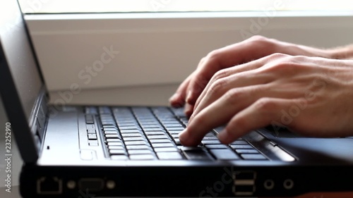 Hands typing on laptop keyboard