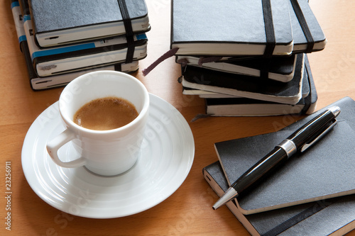Espresso neben Stapel von Notizbüchern, Tagebüchern mit Stift