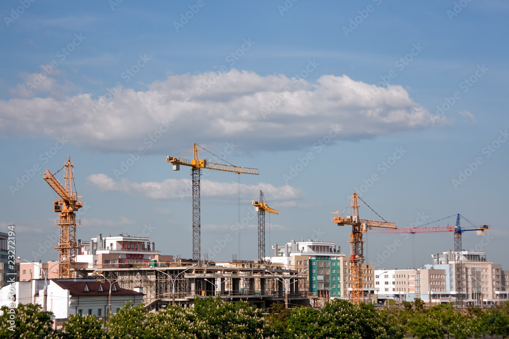 Construction site. Construction cranes on the background of the sky and clouds. Panorama