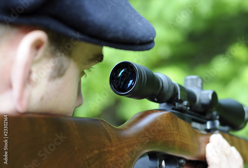 Φωτογραφία Man looking through scope on a rifle gun