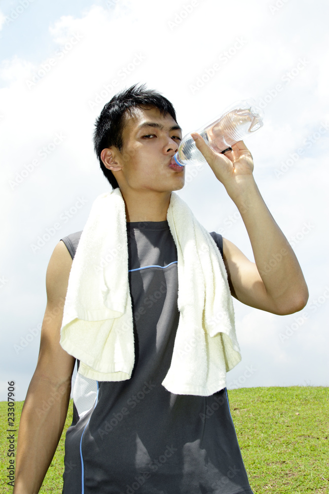 Young Asian man drinking water after a workout session Young Asian man drinking water after a workout session