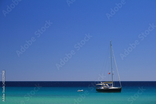 Sailboat on a clear blue sea under a cloudless blue sky © Sunlove