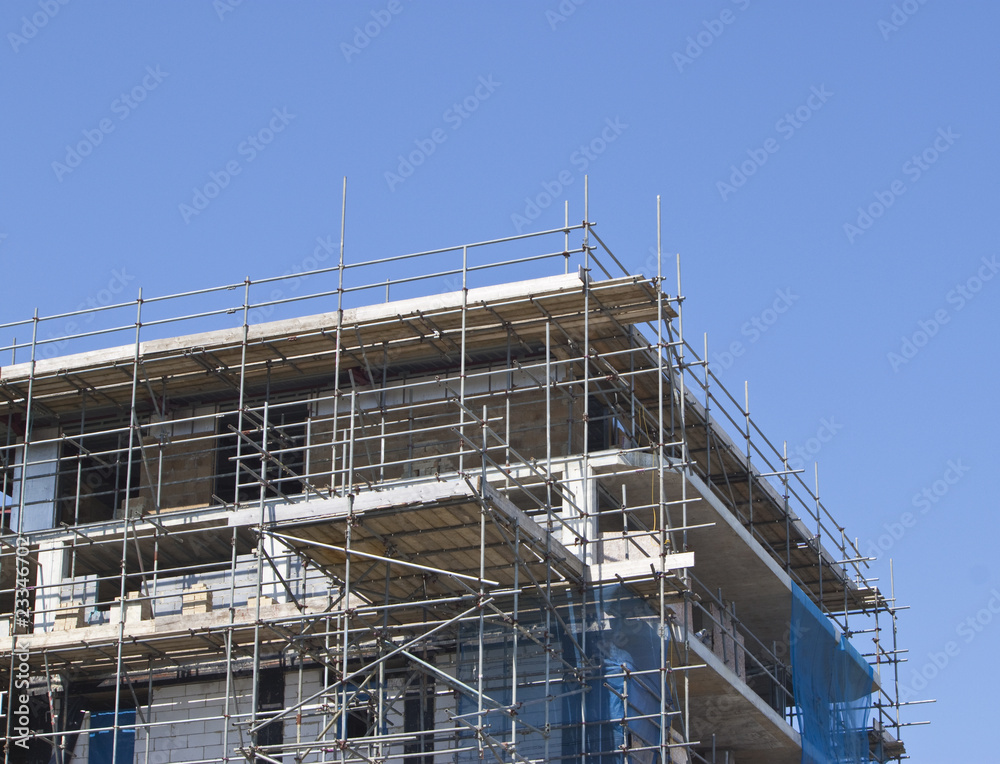 construction with scaffolding against blue sky