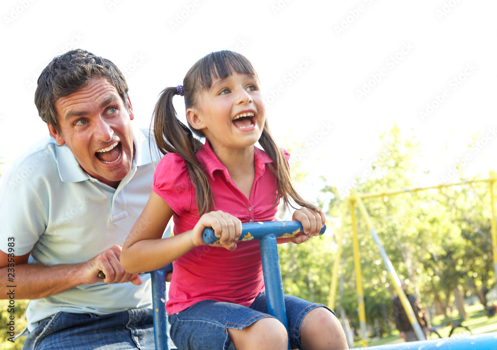 Obraz premium Father And Daughter Riding On See Saw In Playground