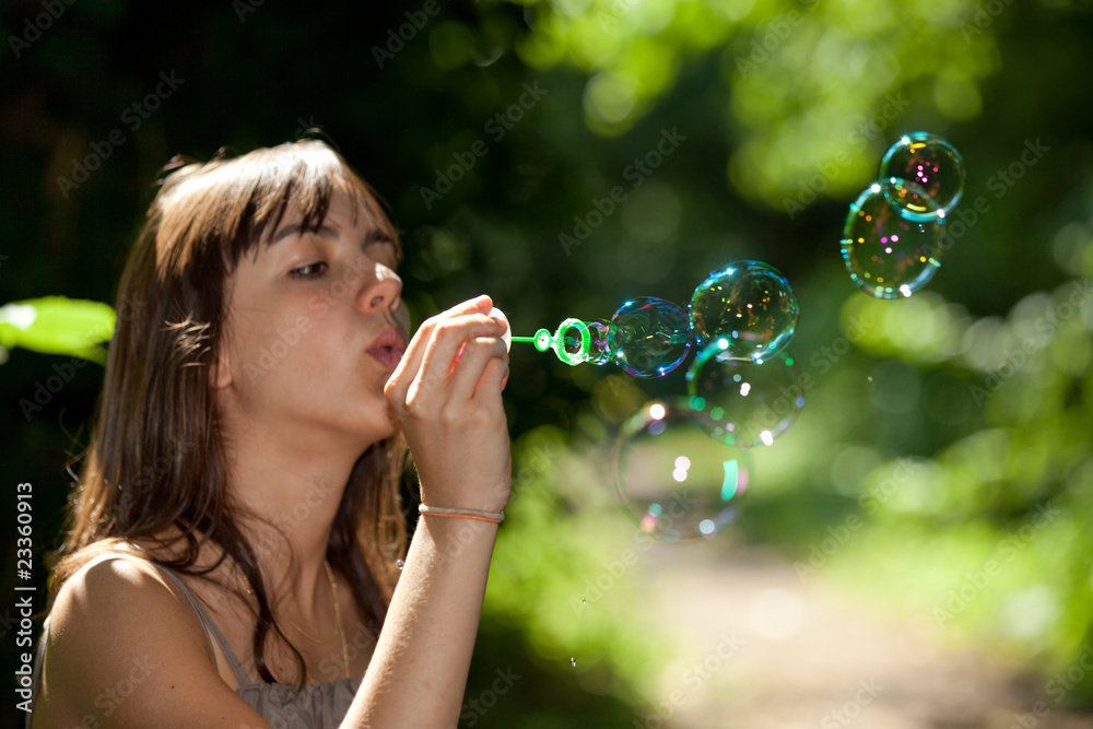 girl blowing bubble soap in nature